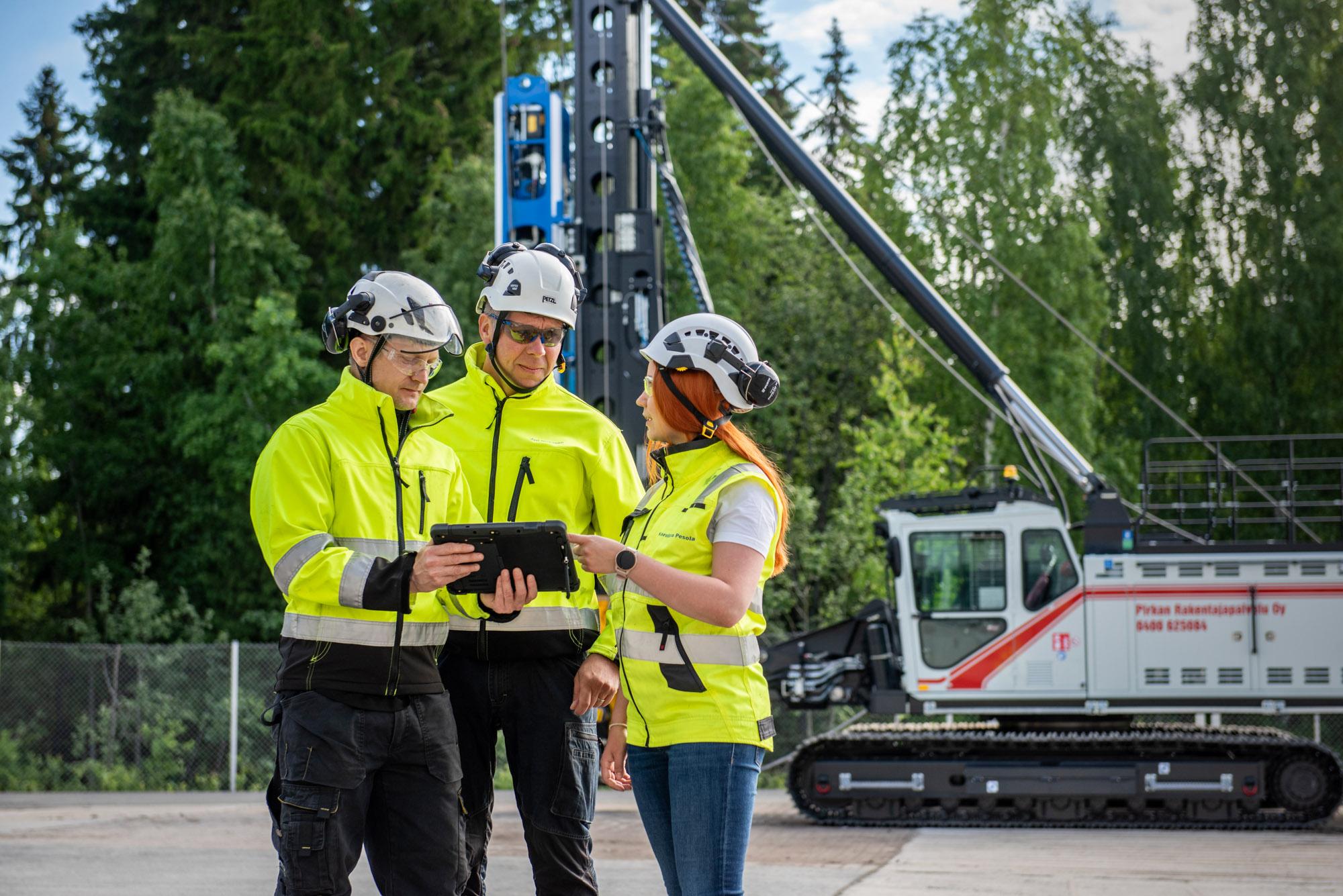 Junttan brand image showing Junttan pile driving rig and three people talking to each other.